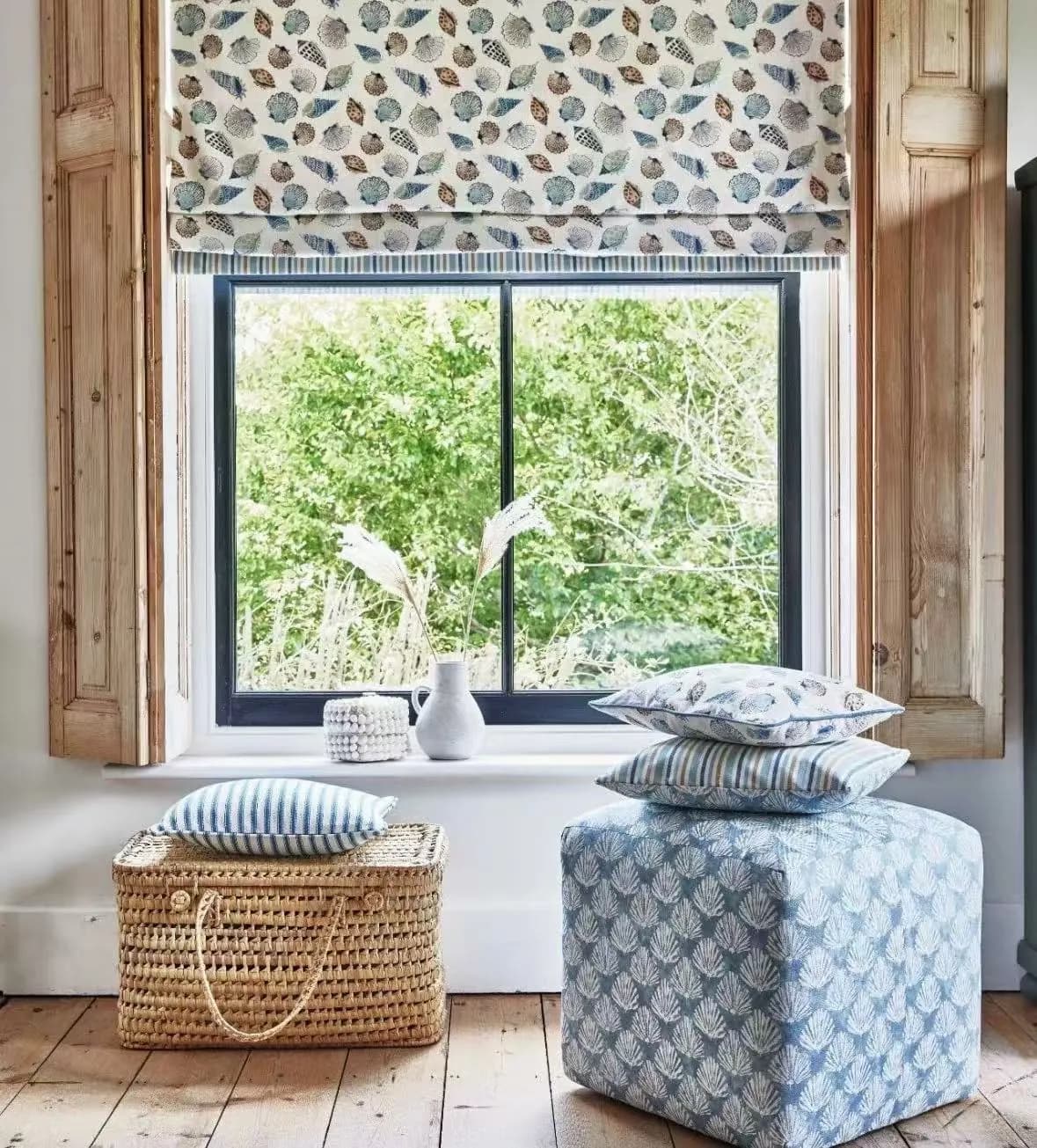 Partly lowered patterned Roman blind coordinated with a cushion and the surrounding interior