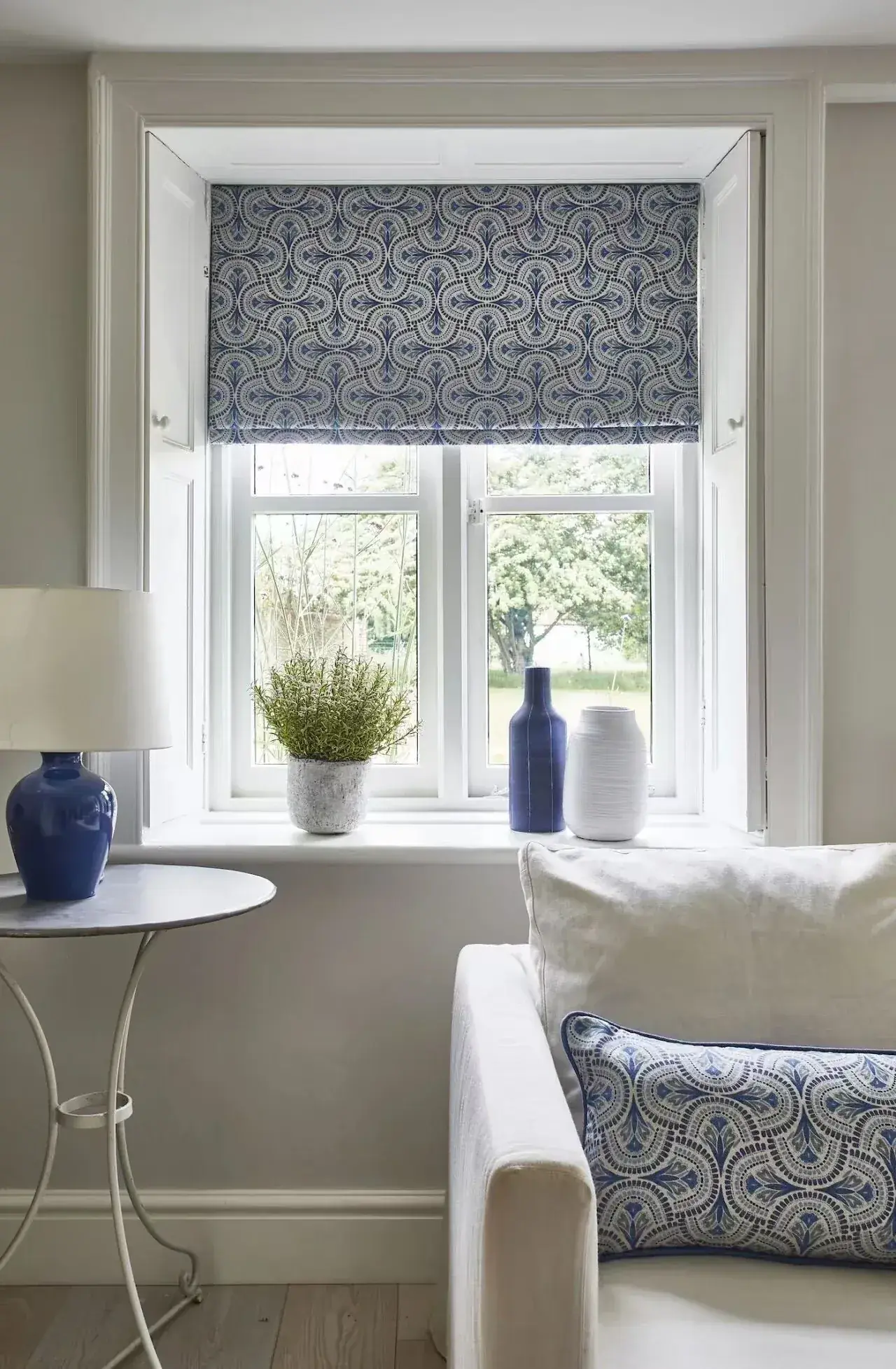 Patterned Roman blind coordinated with furniture at a compact window