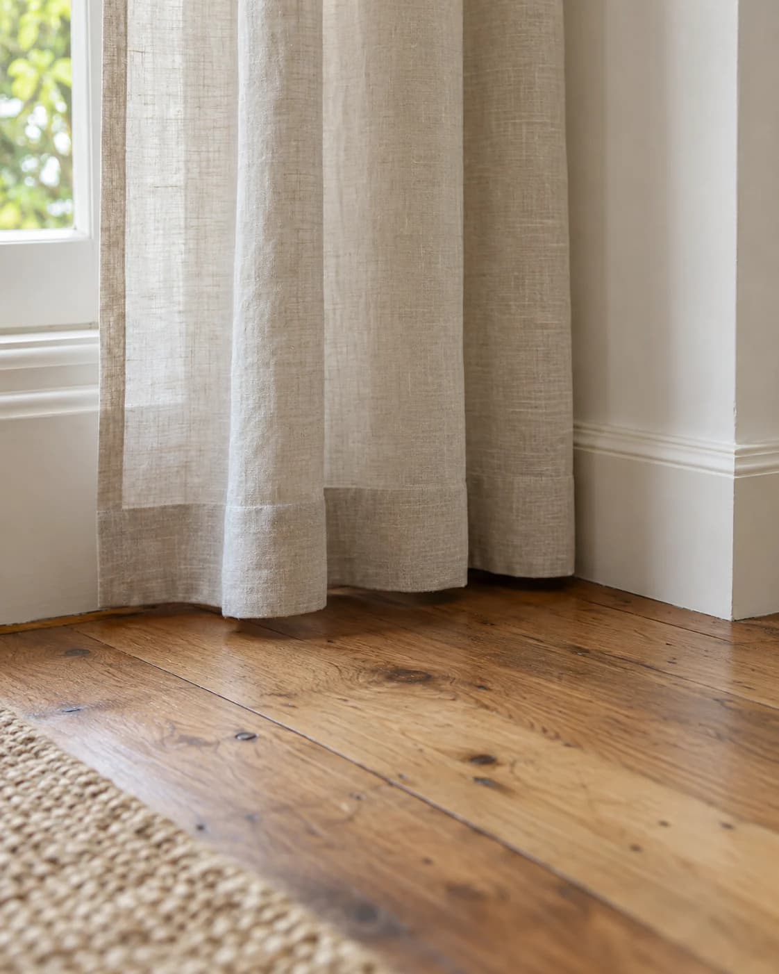 Linen curtain hem finished with precise clearance above a timber floor