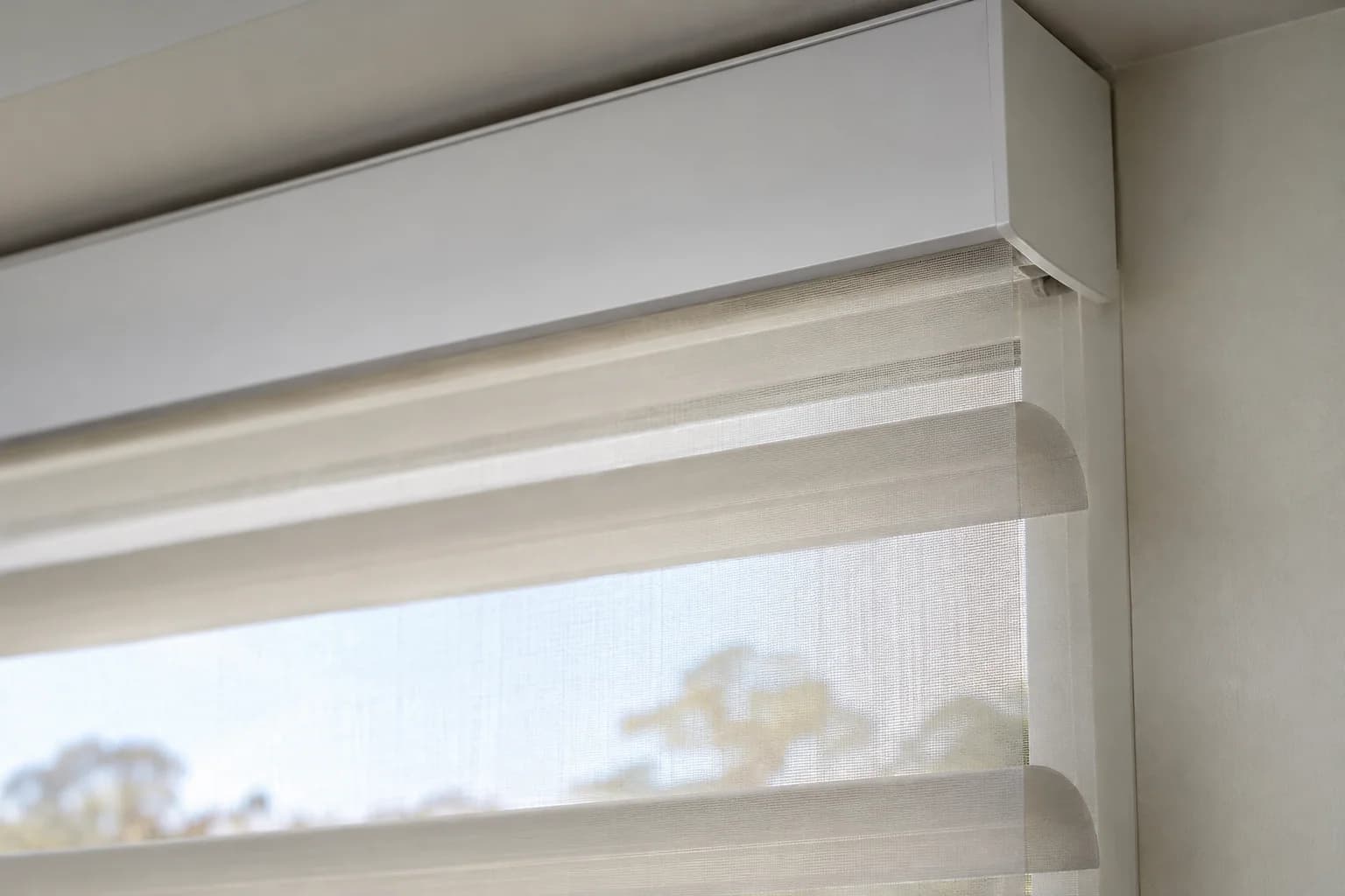 Close view of sheer-vane fabric entering a compact headrail