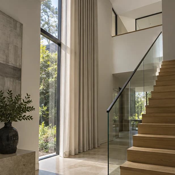 Illustrated tall curtain beside double-height glazing and a stair; motor hardware is not visible