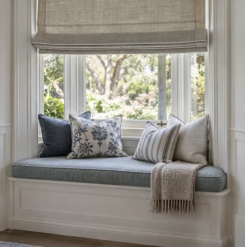 Fitted bay-window cushion below a tailored Roman blind