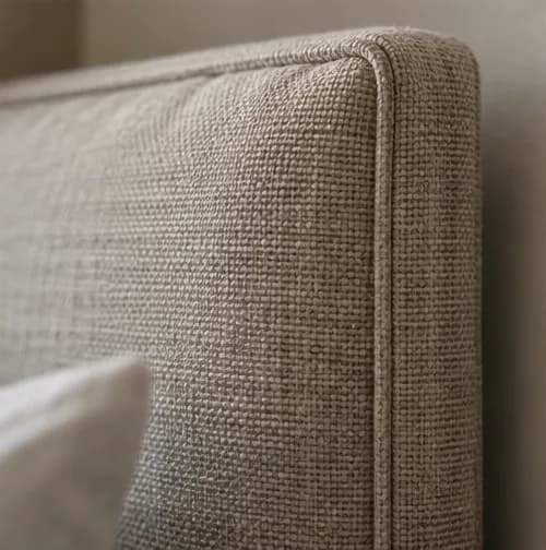 Close view of upholstered bedhead fabric and piping