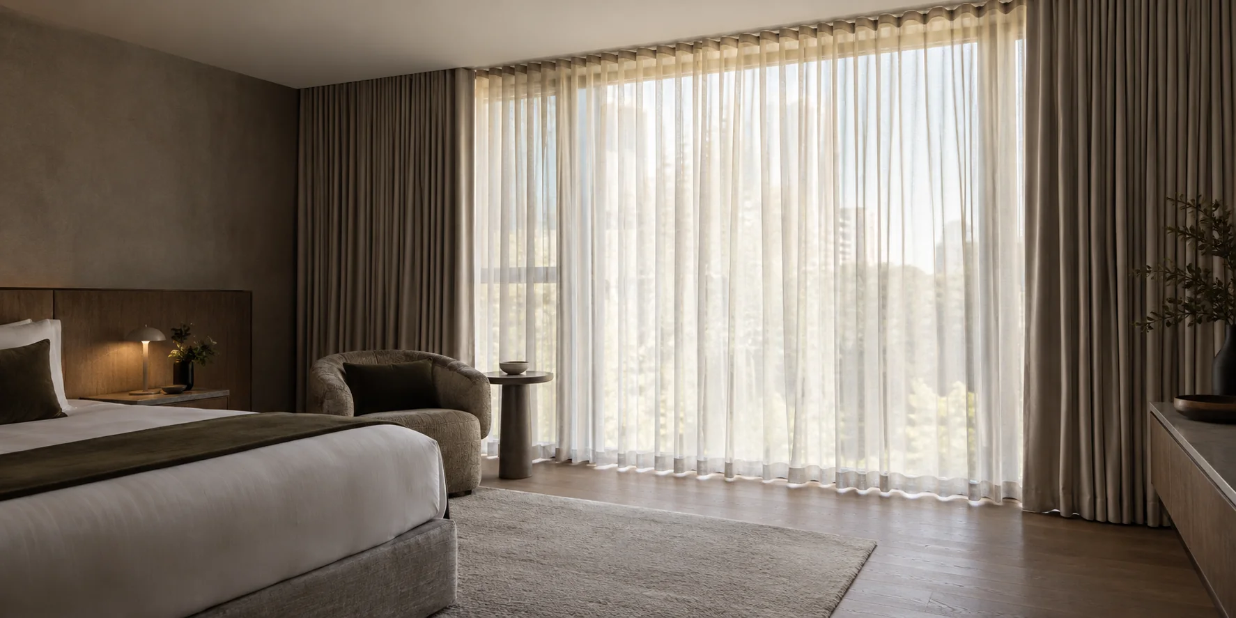 Hotel guest suite with ceiling-mounted sheers and room-darkening curtains