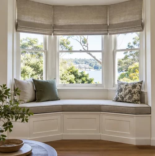 Tailored cushion fitted around a bay window with Roman blinds