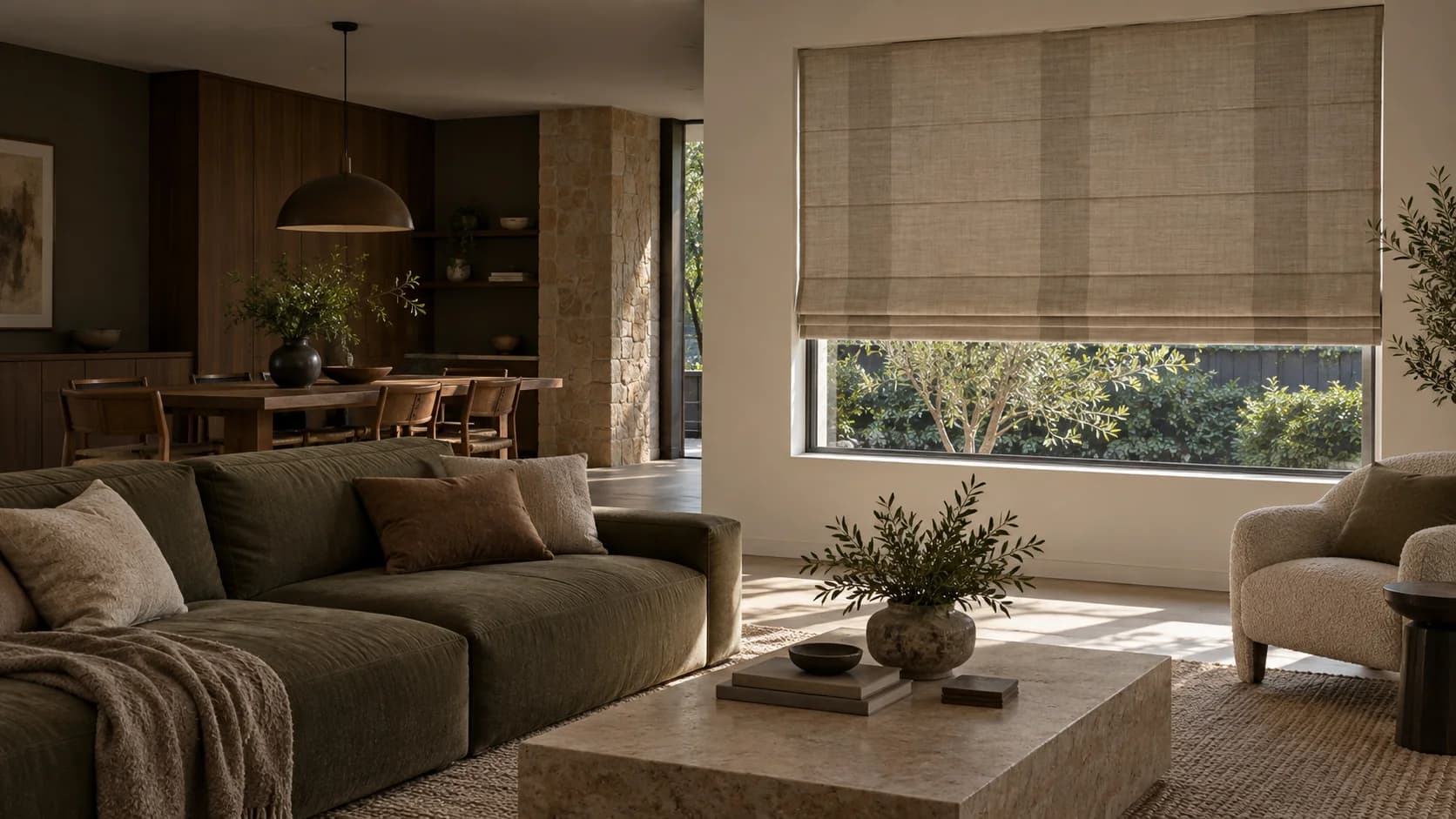 Textured Roman blind lowered over a wide living-room window in a mature timber and stone interior